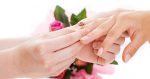One bride sliding the wedding band on the other bride's finger (What to expect at your first same-sex wedding)