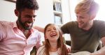 Same Sex Male Couple Reading Book With Daughter At Home Together Whilst Tickling He