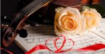 Close-up of a Violin with White Roses and Sheet Music -This list of lesbian wedding songs will have you covered from your walk down the aisle to the very last dance of your reception!