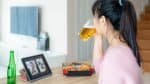 Woman virtual happy hour meeting party and drinking alcohol beer online together with her friend in video conference with digital tablet for a online meeting in video call for social distancing for infection risk.