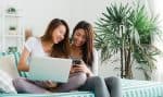 Beautiful young asian women LGBT lesbian happy couple sitting on sofa buying online using laptop a computer and phone in living room at home. LGBT lesbian couple together indoors concept