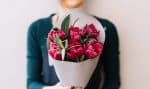 Young woman holding beautiful fresh blossoming flower bouquet of purple tulips and pistachio branche