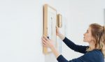 woman hanging wall art on a white wall