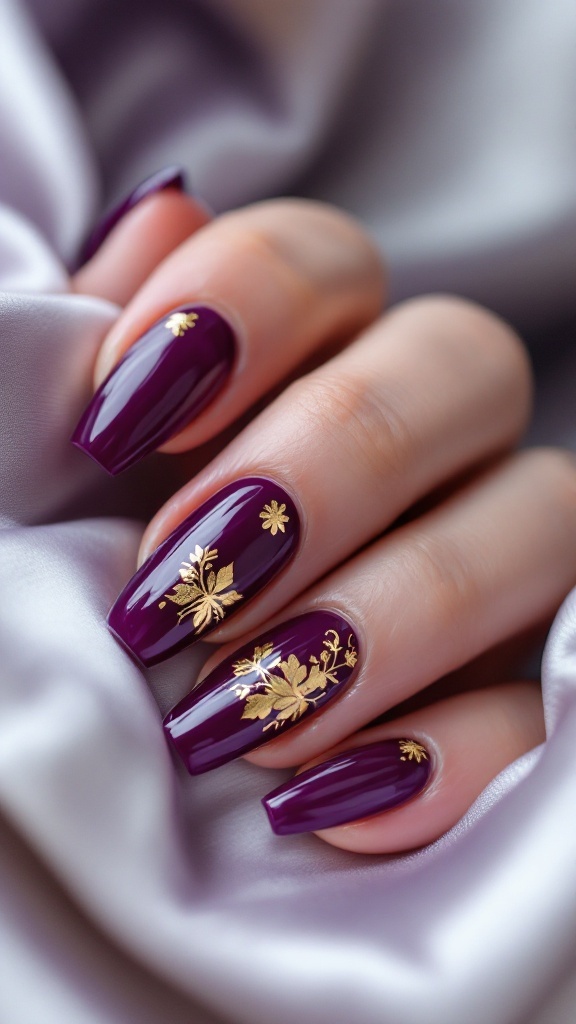 Grape jelly nails with gold foil accents on a hand against a soft fabric backdrop.