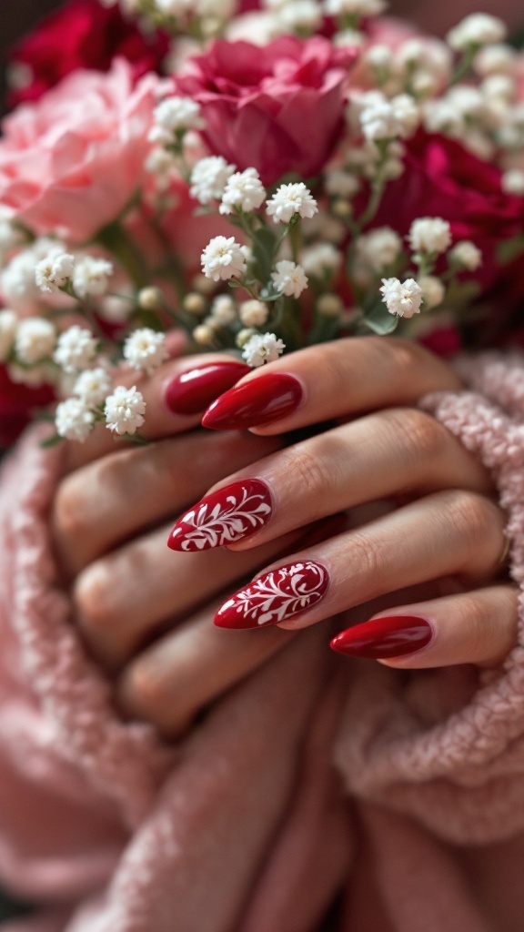 A close-up of almond shape red wedding nails with white floral design, surrounded by pink and red roses.
