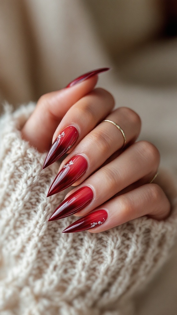 A hand with deep red ombre nails with silver accents, showcasing an elegant gothic wedding nail design.