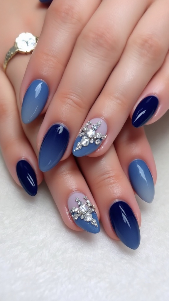 Close-up of a hand with navy blue ombre nails and crystal details, resting on a soft blanket.
