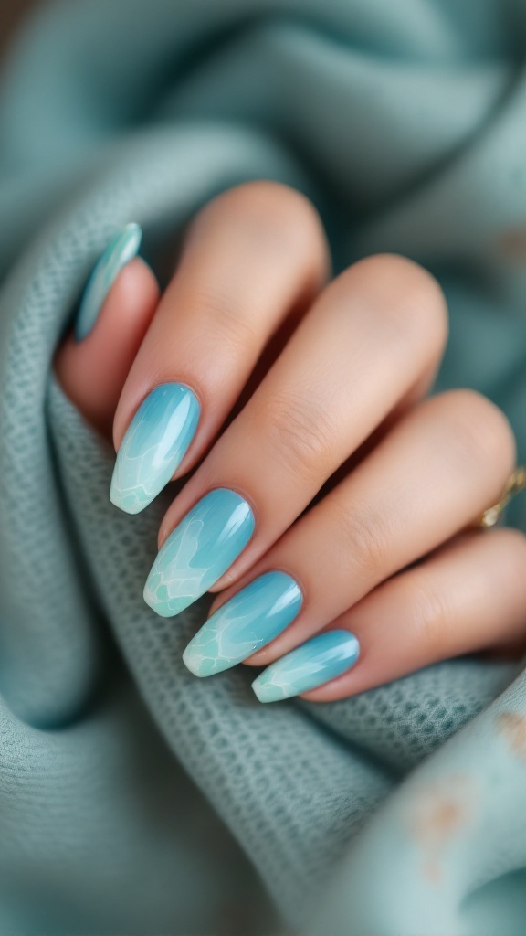 A hand with ocean-inspired blue and green ombre nails, showing a smooth gradient and textured design.