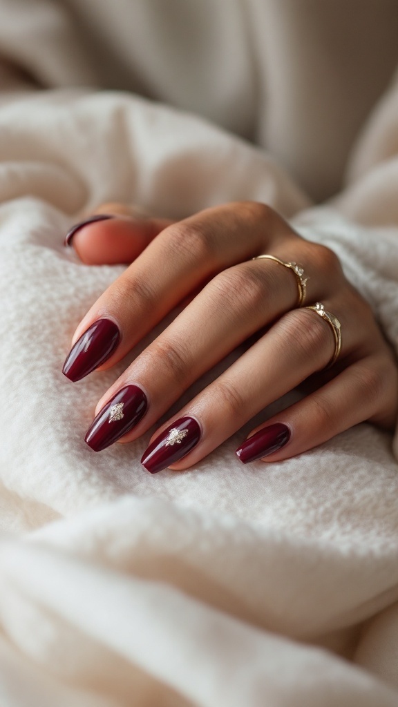 Rich burgundy nails with metallic accents, showcasing a stylish bridal manicure.