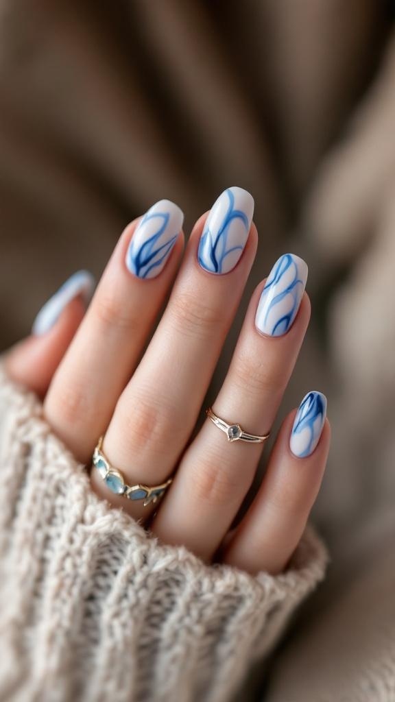 A close-up of blue marble effect acrylic nails with elegant swirls and a cozy knitted sweater.