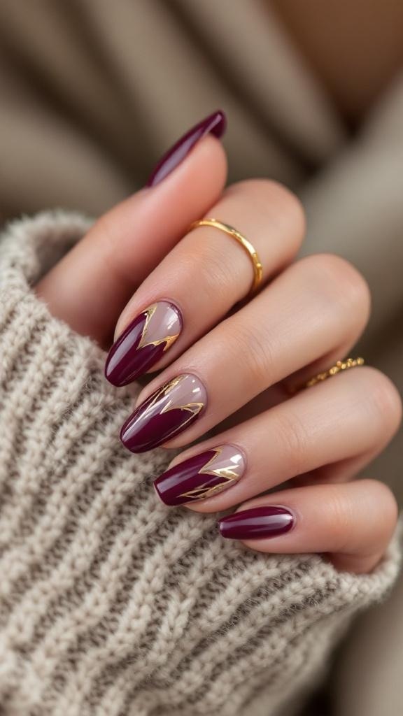Nails painted in cherry wine color with gold foil accents, showcasing a stylish design.