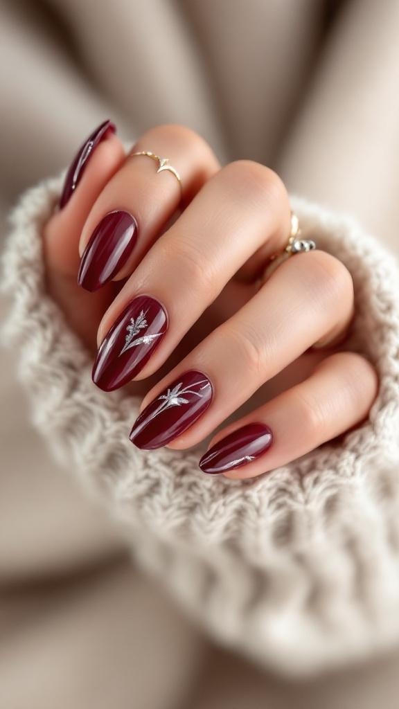 A hand with cherry wine colored nails featuring silver accents, resting on a cozy knitted fabric.