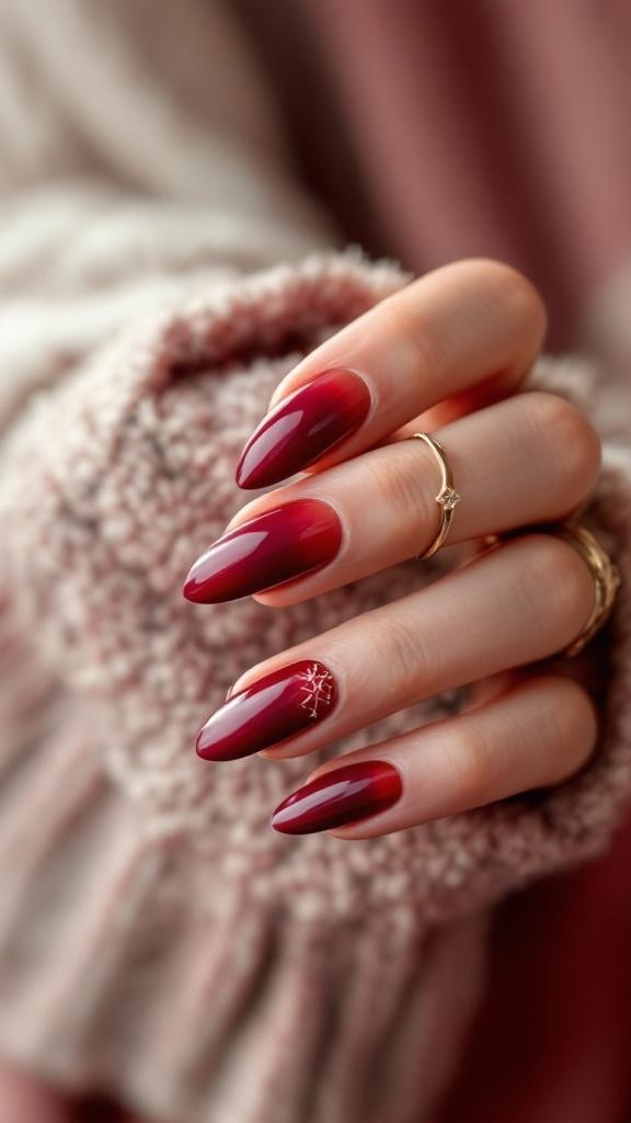 A close-up of cherry wine gradient nails with a glossy finish and a gold accent on one nail.