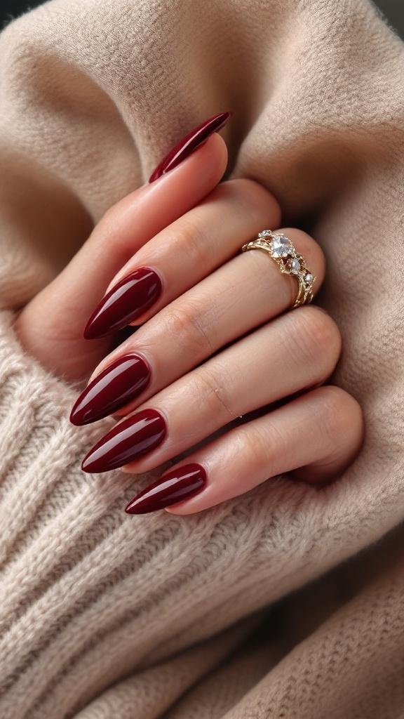 A hand with cherry wine nails and a gold ring, resting on a soft beige fabric.