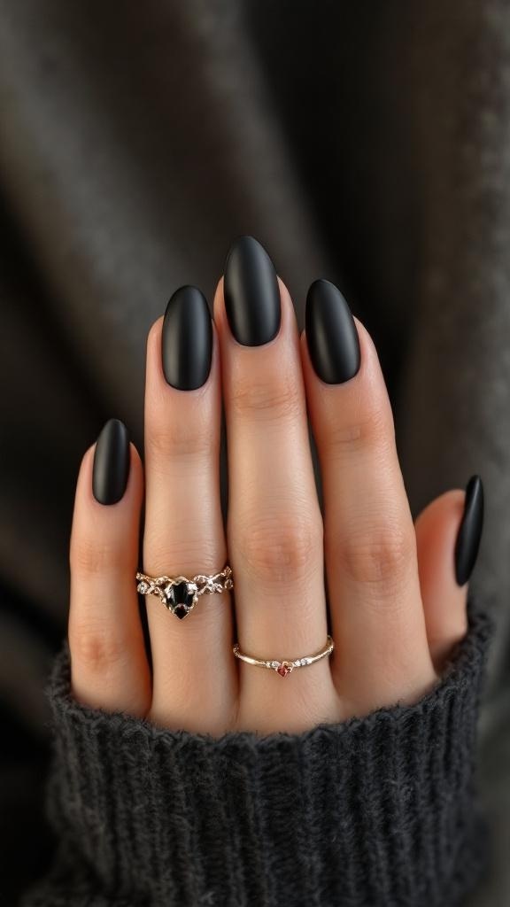 Close-up of chic matte black almond nails with rings on fingers