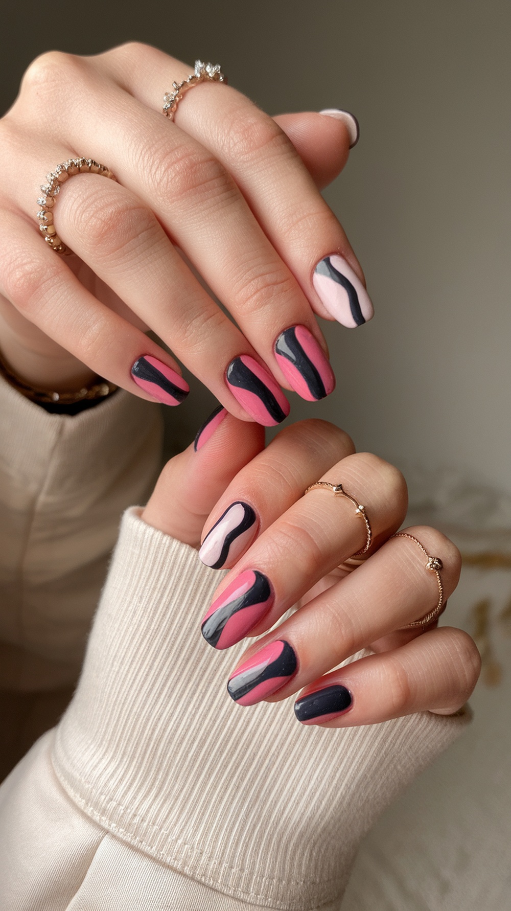 Nail art featuring color-blocking techniques with wavy patterns in pink, gray, and black.