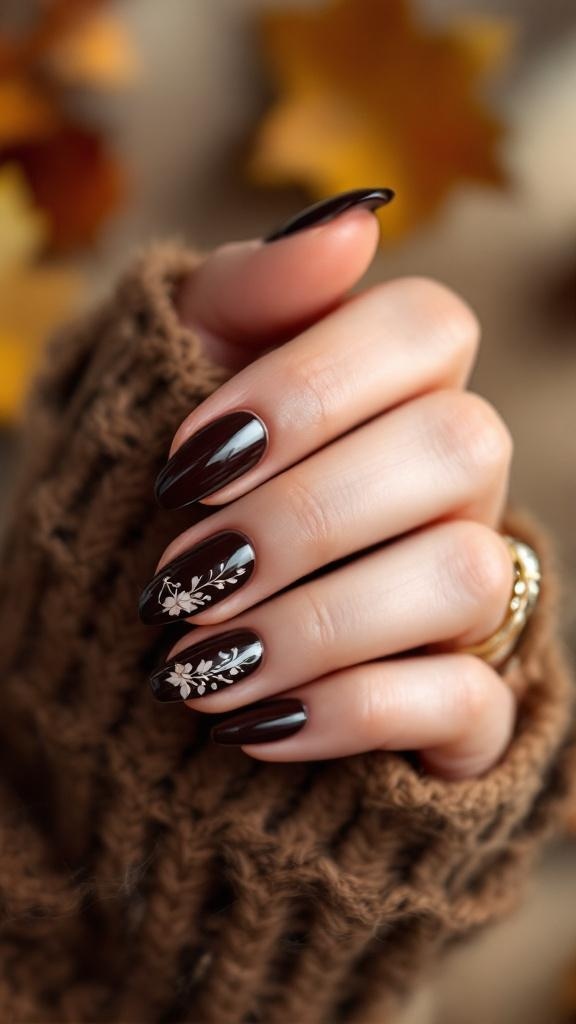 A hand with dark brown nails featuring floral designs, wearing a cozy brown sweater.