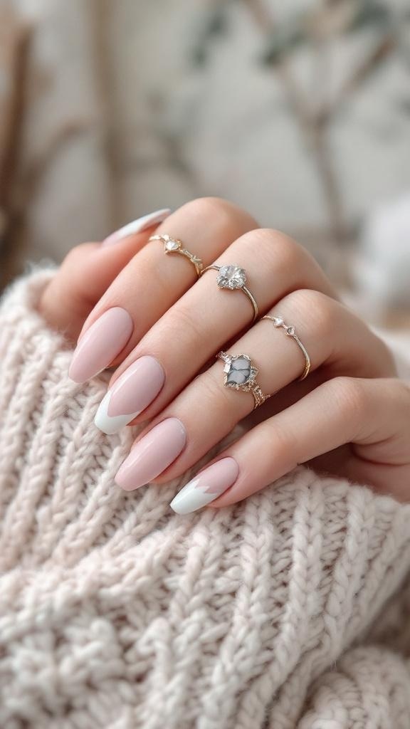 Close-up of short matte finish nails with a light pink base and white tips, adorned with delicate rings.