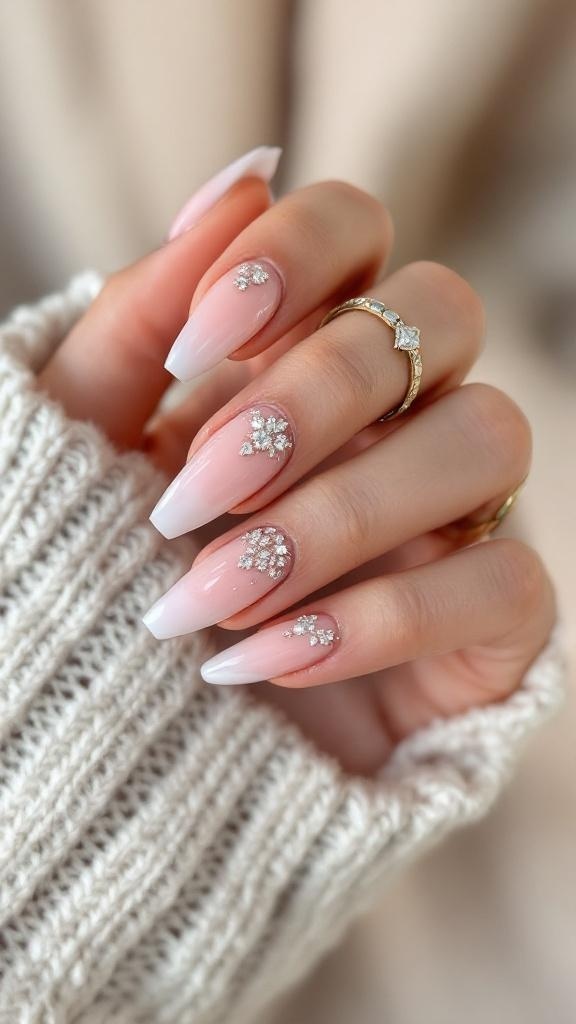 A hand with elegant ombre nails featuring sparkling embellishments, wearing rings and a cozy sweater.