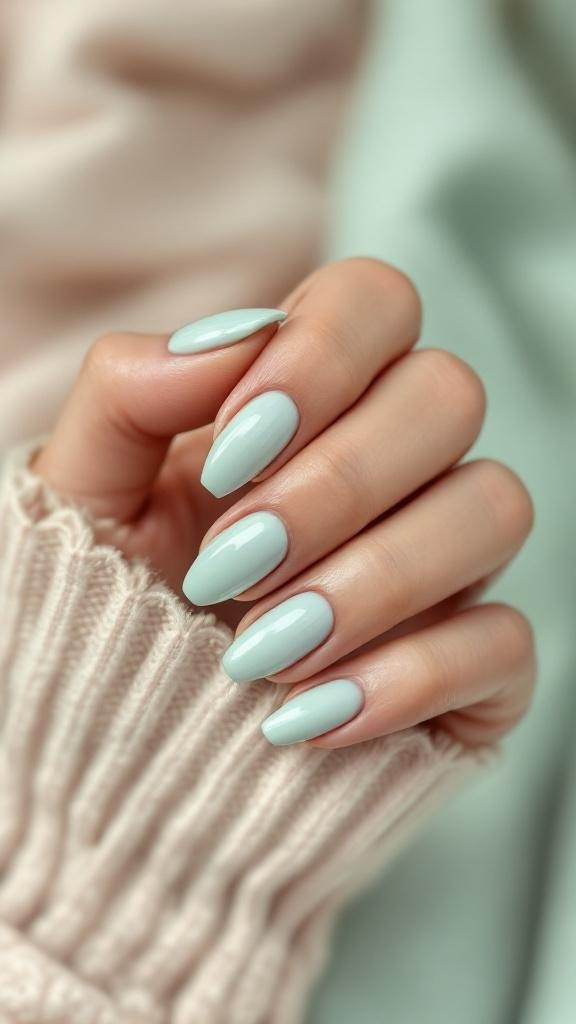 A close-up of a hand with soft mint green nails, resting on a cozy sweater.