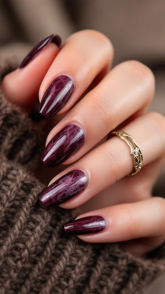 Close-up of textured cherry wine nails with a glossy finish, featuring a marbled design and delicate ring.