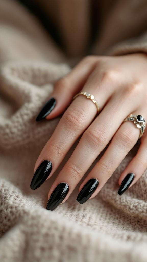 A hand with black stiletto nails resting on a soft, textured surface, adorned with delicate rings.