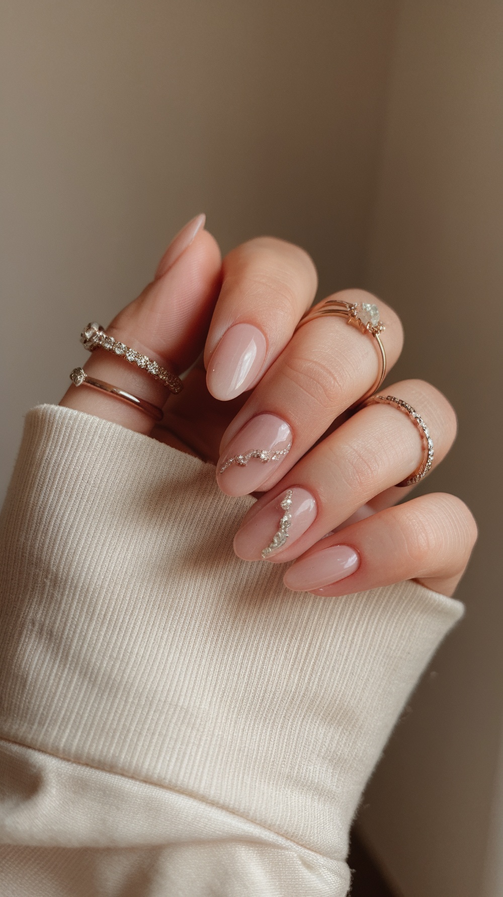 Close-up of elegantly manicured nails with metallic accents and rings