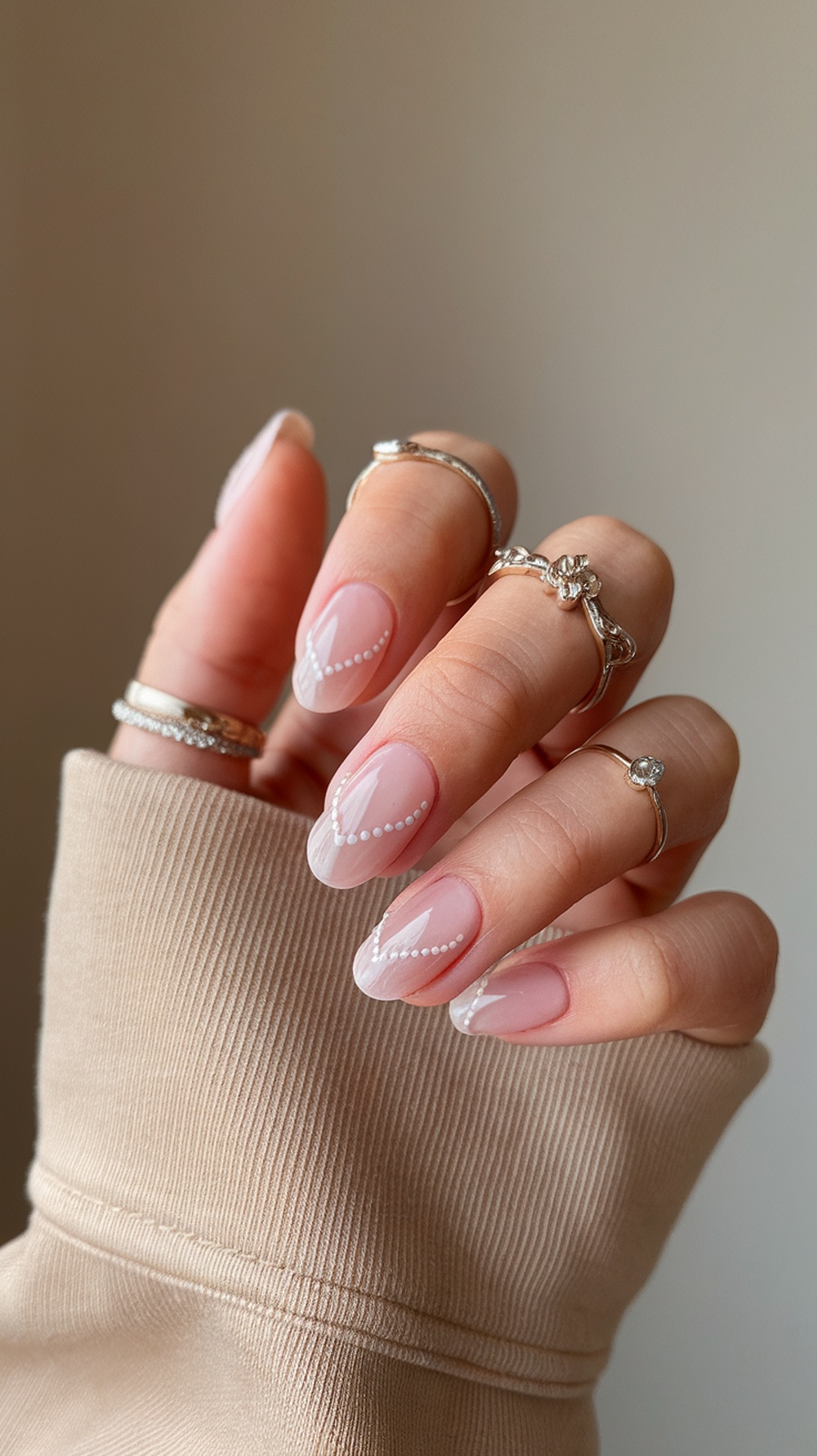 Elegant wedding nails with a soft pink base and white accents, featuring delicate pearl designs.